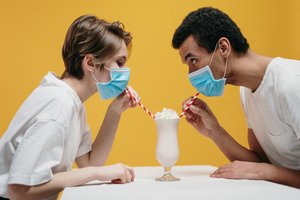 couple wearing facemasks drinking milkshake